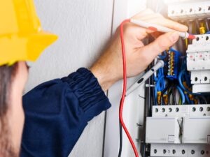 Man in hard hat working on an electrical panel.