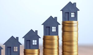 a stack of coins with a house model on top